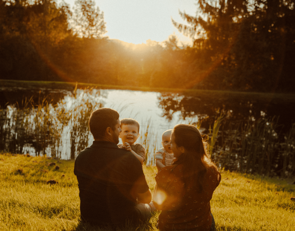 Family sitting in front of pond during golden hour.